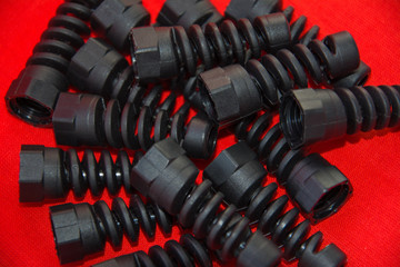 Black plastic and rubber parts of automotive manufacturing by high precision mold injection in the industrial factory. Spare part in the form of a spiral spring on a red surface. Selective soft focus.