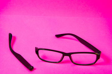 Broken bow near glasses on pink background