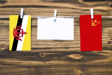 Hanging flags of Brunei and Soviet Union attached to rope with clothes pins with copy space on white note paper on wooden background.Diplomatic relations between countries.