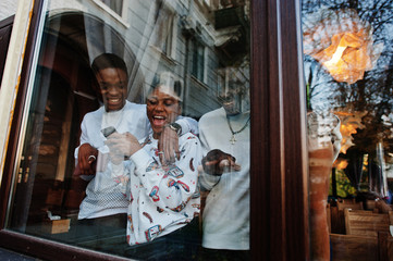 Happy african friends chatting in cafe. Group of black peoples meeting in restaurant against glass of window.