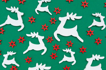 Wooden handmade Christmas decorations white Deers and red Stars with a pattern on a green isolated background. Flat lay, top view. Merry Christmas and Happy New Year concept. Minimalistic style