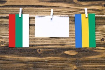 Hanging flags of Bulgaria and Gabon attached to rope with clothes pins with copy space on white...