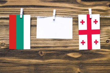 Hanging flags of Bulgaria and Georgia attached to rope with clothes pins with copy space on white...