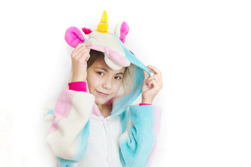 Positive young girl posing in funny pajamas. Girl in unicorn kigurumi isolated on white background © Наталья Маяк
