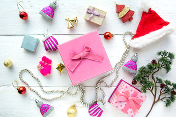 Christmas background top view. Pink and red gift boxes. Coniferous branches and Christmas toys on a background of a white wooden board. New Year 2020