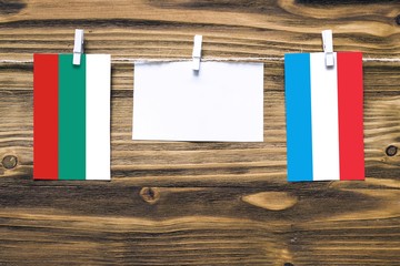 Hanging flags of Bulgaria and Luxembourg attached to rope with clothes pins with copy space on...