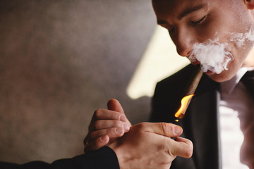 elegant man wearing suit and white shirt smoking cigar indoor shot, closeup, selective focus. cigar...