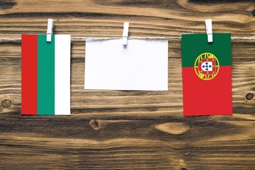 Hanging flags of Bulgaria and Portugal attached to rope with clothes pins with copy space on white...