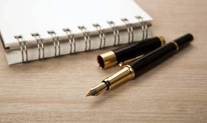 golden fountain pen near the notepad with paper closeup