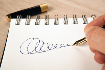 golden fountain pen in the hand and a signature on the paper
