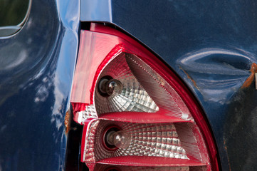 tail light car. broken rear brake light. blue passenger car. dent and scratch on the rear fender....