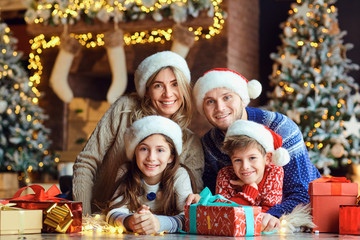 Happy family smiling with gifts in a room at Christmas