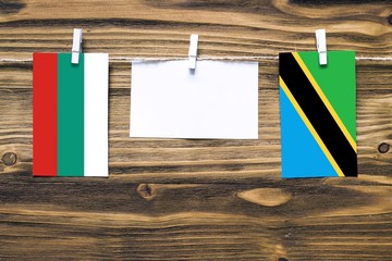 Hanging flags of Bulgaria and Tanzania attached to rope with clothes pins with copy space on white...