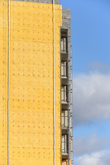 Construction of a high residential building and insulation of its external wall with special heat-insulating material. Wall with thermal insulation against the blue sky