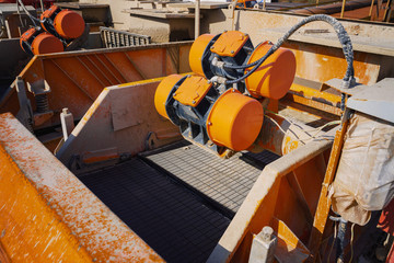 Shale shaker on an offshore oil rig. Shale shaker screen close up view with drill cutting flow out from oil base mud. Separators are end. Equipment for oil separation.