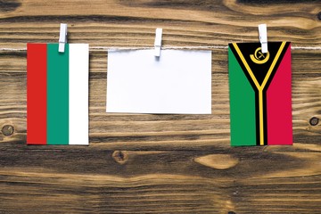 Hanging flags of Bulgaria and Vanuatu attached to rope with clothes pins with copy space on white...