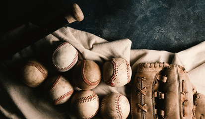 Moody baseball equipment on grunge background, flat lay of used balls with bat and glove.