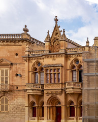 Fototapeta na wymiar Neo-gothic Casa Gourgion in Mdina, Malta, with lancet arches, rose windows, carved ornamentation and the coat of arms for the Knights Hospitaller.