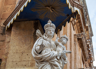 Fototapeta premium Blessed Virgin Mary and baby Jesus statue at the corner of Annunciation Church, also known as The Carmelite Church in Mdina, Malta.