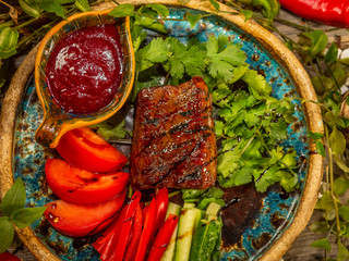 Delicious meat steak with vegetables, tomato and cucumber sliced in strips on craft dishes