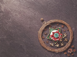 Christmas composition. A wicker wreath of branches is on a dark cement background. Nearby are various Christmas decorations.