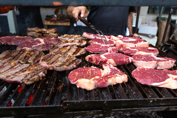 Closeup of delicious beef steaks roasted on barbecue grill. Organic meat roasted on rustic charcoal barbecue. Concept of food, gastronomy, recipes, healthy eating and health.