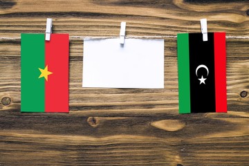 Hanging flags of Burkina Faso and Libya attached to rope with clothes pins with copy space on white...