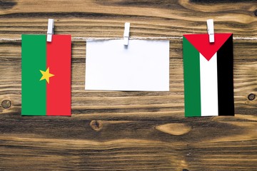 Hanging flags of Burkina Faso and Palestine attached to rope with clothes pins with copy space on...