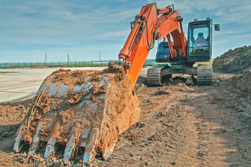 Crawler excavator at a construction site. Excavator with a bucket lowered down.