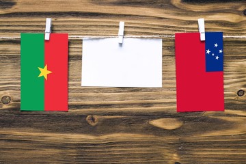 Hanging flags of Burkina Faso and Samoa attached to rope with clothes pins with copy space on white...