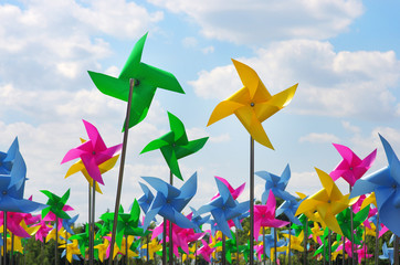 Colourful children's pinwheels in the blue sky with clouds