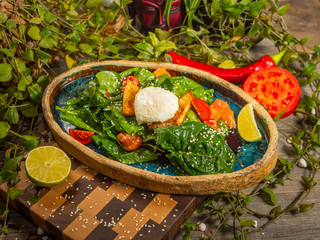 Tasty salad with egg, tomato, guacamole sauce, with crackers, lime and herbs on a craft plate