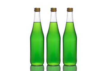 Three large glass bottles with green liquid stand on a mirror surface on a white background in the middle.