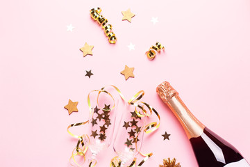 Two champagne glasses with confetti and streamers, golden champagne bottle, green natural fir tree on pastel pink background, copy space. Festive flat lay composition for Christmas or New Year