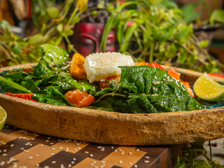 Tasty salad with egg, tomato, guacamole sauce, with crackers, lime and herbs on a craft plate