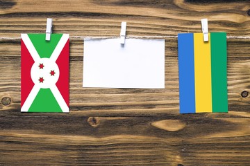 Hanging flags of Burundi and Gabon attached to rope with clothes pins with copy space on white note...