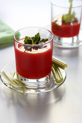 One glass with tomato juice and parsley decoration, a second glass with tomato juice and celery sprig.