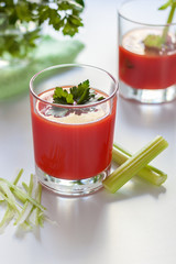 One glass with tomato juice and parsley decoration, a second glass with tomato juice and celery sprig.