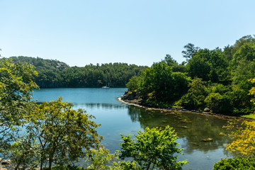 Obraz premium Sailboat anchored in a protected anchorage. Lush and green scenary surrounding the bay