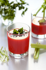 One glass with tomato juice and parsley decoration, a second glass with tomato juice and celery sprig.
