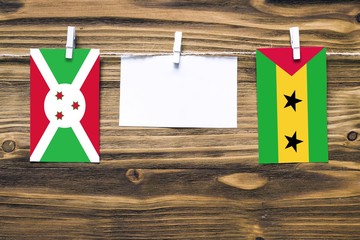 Hanging flags of Burundi and Sao Tome And Principe attached to rope with clothes pins with copy...