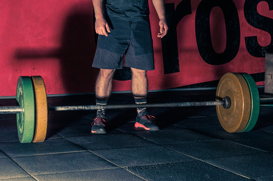 young athlete is resting between sets in a barbell lift, hands in gym shalk, photo in a dark key, concept of sports and motivation