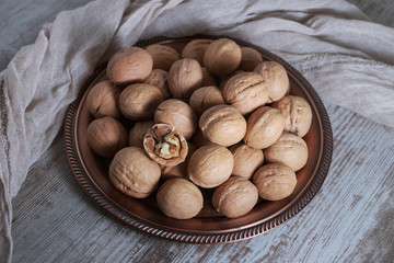 Top view of walnuts in a copper dish on a wooden rustic table.