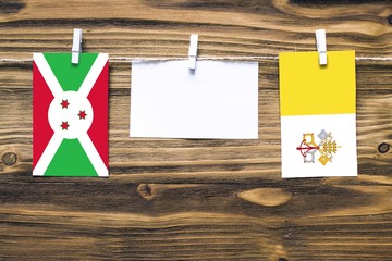 Hanging flags of Burundi and Vatican City attached to rope with clothes pins with copy space on...