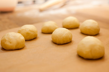 Fototapeta na wymiar Raw homemade buns on kitchen table in the making