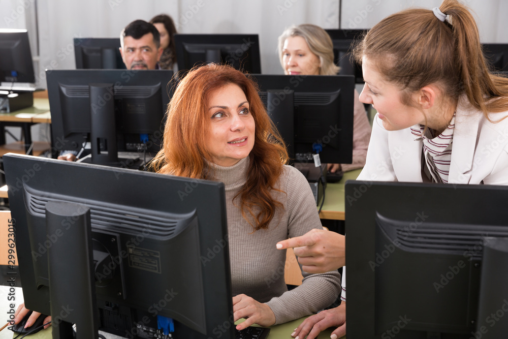 Wall mural female teacher helping smiling mature woman