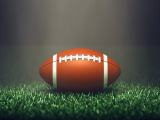 American football ball on grass lit by spotlight, Sport stadium
