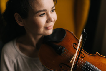 Close-up portrait of beautiful smiling young woman musician playing the violin