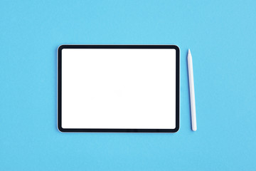 Tablet mockup with white pencil on blue background. Top view. Copy space.