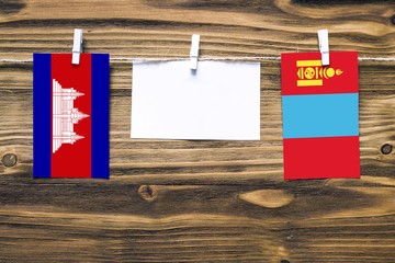 Hanging flags of Cambodia and Mongolia attached to rope with clothes pins with copy space on white...